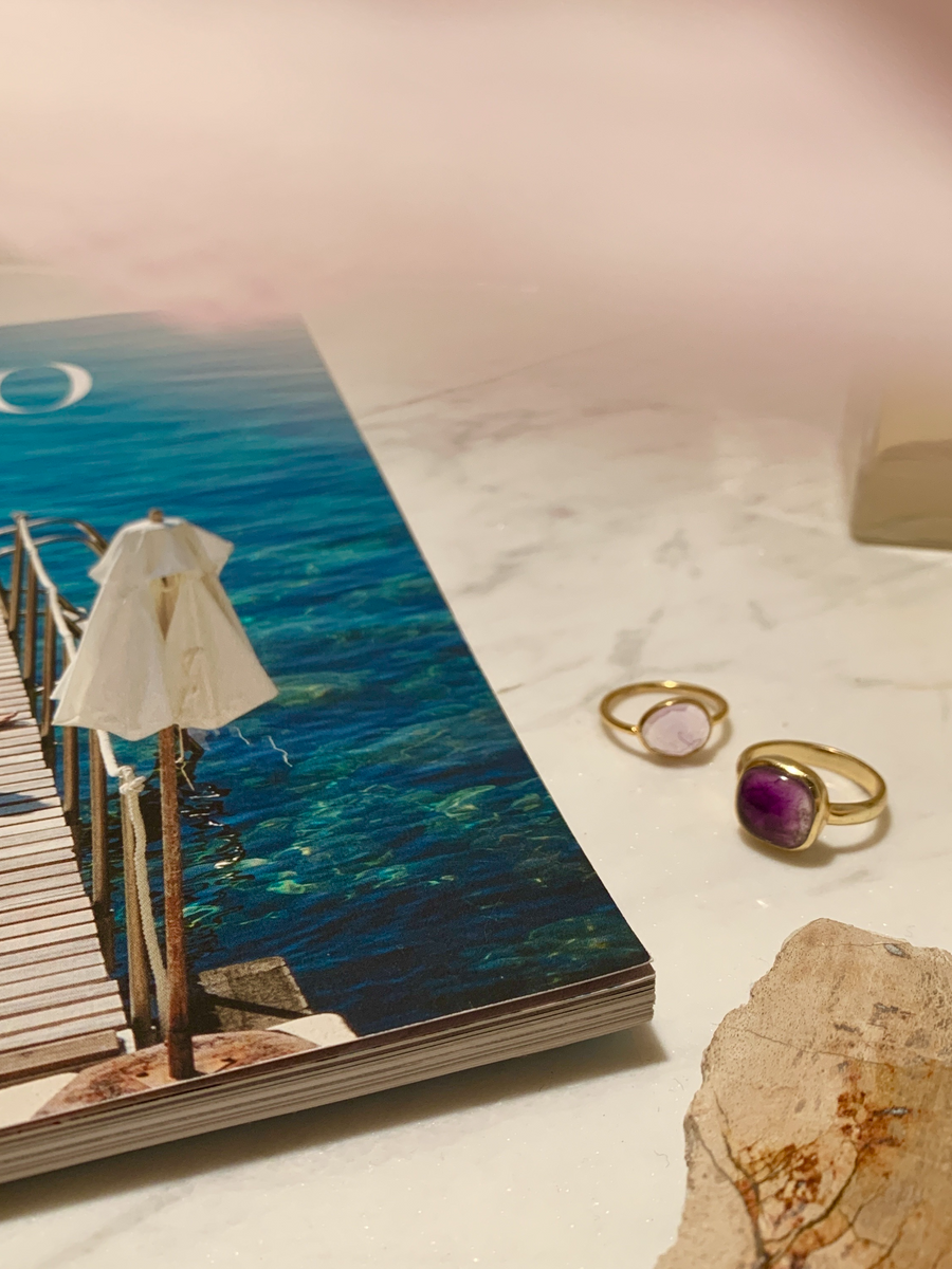 綺麗な海の写真アルバムの隣にある色の違う２つのアメジストの指輪