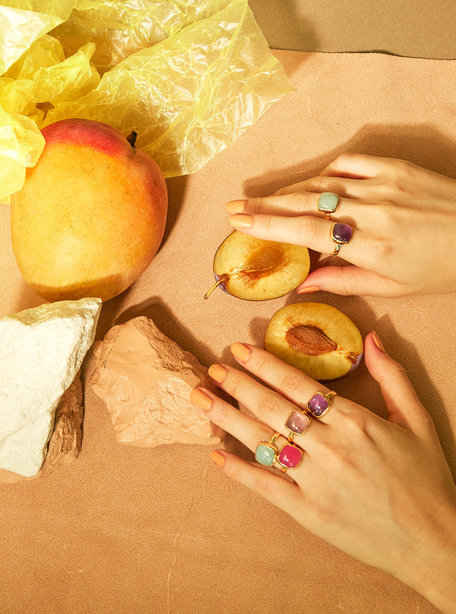 フルーツを手に取る指に着けられた6つの天然石の指輪